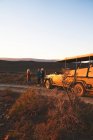 Safari grupo turístico y vehículo todoterreno en la carretera al atardecer Sudáfrica - foto de stock