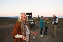 Retrato feliz mujer mayor bebiendo champán en safari - foto de stock
