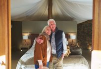 Portrait heureux couple de personnes âgées étreignant dans la chambre d'hôtel safari lodge — Photo de stock