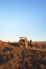 Safari groupe de visite debout à l'extérieur du véhicule hors route dans les prairies ensoleillées — Photo de stock