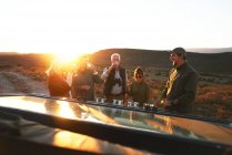 Safari grupo de turismo bebendo champanhe ao pôr do sol — Fotografia de Stock