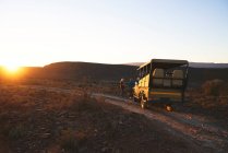 Safari veículo off-road e turistas ao pôr do sol na estrada África do Sul — Fotografia de Stock