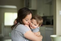 Affectionate mother hugging toddler daughter — Stock Photo