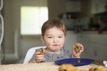 Portrait of cute toddler girl eating messy muffin — Stock Photo