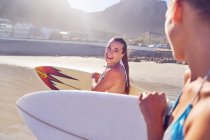 Happy young female surfer friends with surfboards on beach — Stock Photo