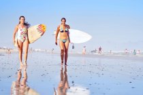 Портрет уверенных молодых женщин-серферов на солнечном пляже океана — стоковое фото