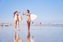 Happy jeune femme surfeuse amis high fiving sur la plage ensoleillée — Photo de stock