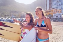 Щасливі молоді жінки-серфери з дошками для серфінгу на сонячному пляжі — стокове фото