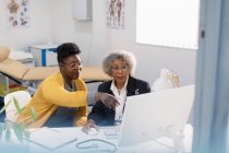 Female doctor and patient meeting at computer in doctors office — Stock Photo