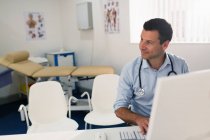 Médico masculino confiante trabalhando no computador em consultório de médicos — Fotografia de Stock