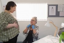 Médico femenino examinando a una mujer embarazada en el consultorio médico - foto de stock