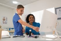 Female pediatrician and boy patient using computer in doctors office — Stock Photo