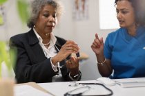 Female doctor teaching diabetic senior patient how to use glucometer — Stock Photo