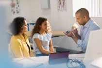 Pediatra masculino enseñando a paciente niña cómo usar inhalador en consultorio médico - foto de stock