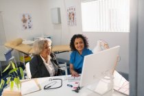 Жінка-лікар зустріч зі старшим пацієнтом за комп'ютером в офісі лікарів — стокове фото