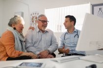 Doctor meeting with senior couple at computer in doctors office — Stock Photo