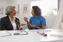 Женщина-врач учит пожилого пациента, как использовать глюкометр в офисе врача — стоковое фото
