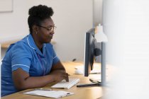 Enfermeira a trabalhar no computador no consultório médico — Fotografia de Stock