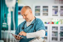 Médico varón usando tableta digital en el hospital - foto de stock