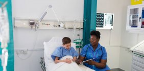 Женщина-медсестра разговаривает с пациентом в палате больницы — стоковое фото