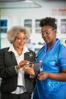 Doctora y enfermera usando tableta digital en clínica - foto de stock