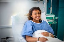 Портрет усміхненої дівчини-пацієнтки в лікарняному ліжку — стокове фото