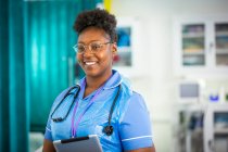 Enfermera confiada en retratos con tableta digital en el hospital - foto de stock