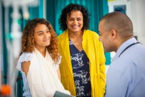 Male pediatrician talking to girl patient with arm in sling in examination room — Stock Photo
