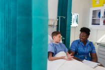 Enfermeira mulher conversando com menino paciente no quarto do hospital — Fotografia de Stock