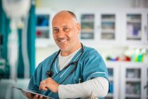 Portrait médecin masculin confiant avec tablette numérique à l'hôpital — Photo de stock