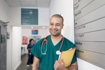 Retrato sonriente, confiado cirujano masculino en el pasillo del hospital - foto de stock