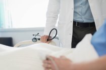 Doctor making rounds, checking on patient in hospital room — Stock Photo