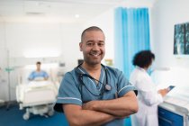 Enfermero masculino sonriente y confiado en el retrato en la habitación del hospital - foto de stock