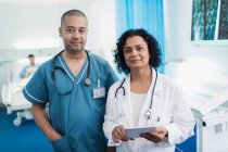 Portrait confident doctor and nurse with digital tablet in hospital room — Stock Photo