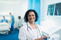 Портрет усміхається, впевнена жінка - лікар користується цифровим планшетом у лікарняній палаті — стокове фото