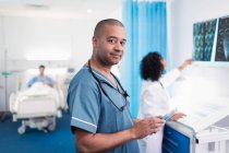 Портрет уверенный, улыбающийся доктор с помощью цифрового планшета в больничной палате — стоковое фото