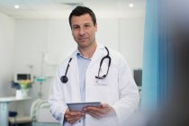 Портрет уверенный мужчина врач с помощью цифровой таблетки в больничной палате — стоковое фото