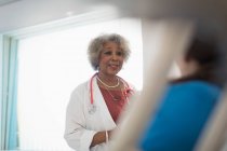 Female senior doctor making rounds, talking with patient in hospital room — Stock Photo