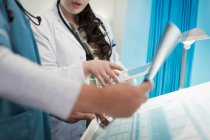 Лікарі з цифровим планшетом обговорюють рентген в лікарняній кімнаті — стокове фото