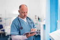 Чоловік лікар використовує цифровий планшет у лікарняній кімнаті — стокове фото