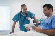 Krankenschwester im Gespräch mit Patientin mit digitalem Tablet im Krankenhausbett — Stockfoto
