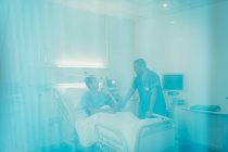 Чоловіча медсестра говорить з пацієнтом у лікарняній кімнаті — стокове фото