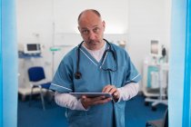 Portrait confident, serious male doctor using digital tablet in hospital room — Stock Photo
