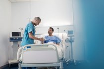 Médecin masculin avec tablette numérique faisant des rondes, parler avec le patient dans la chambre d'hôpital — Photo de stock