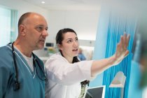Médicos discutiendo rayos X en la habitación del hospital - foto de stock