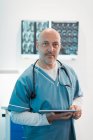 Портрет впевненого лікаря-чоловіка, який використовує цифровий планшет у лікарні — стокове фото