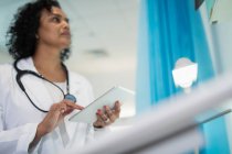 Зосереджена жінка - лікар за допомогою цифрового планшета у лікарняній палаті. — стокове фото