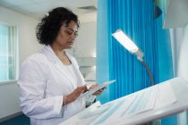 Жіночий лікар у лікарняній палаті користується цифровою табличкою. — стокове фото