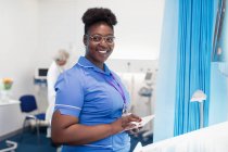 Портрет уверенной женщины-медсестры с помощью цифрового планшета в больничной палате — стоковое фото