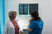 Female doctor and nurse discussing x-rays in in hospital — Stock Photo